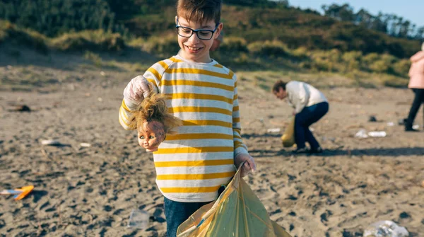 ビーチを掃除しながら人形の頭を示す男の子 — ストック写真