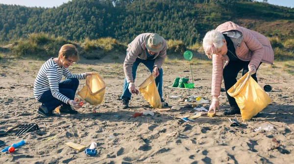Voluntarios mayores limpiando la playa — Foto de Stock