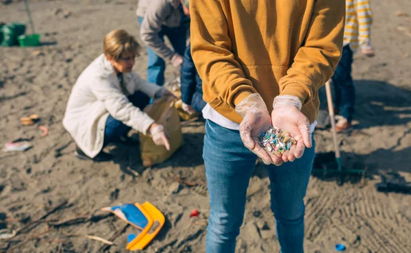 Händerna med mikroplast på stranden — Stockfoto