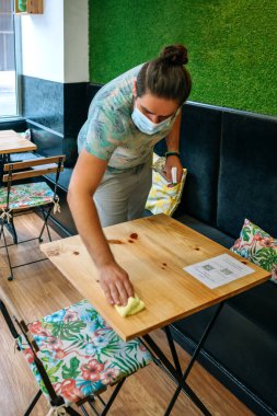 Garson Coronavirus yüzünden masaları dezenfekte ediyor.