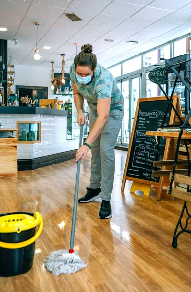 Worker mopping the floor of a coffee shop