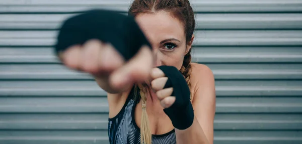 Sportovní žena dívá na kameru a punching — Stock fotografie