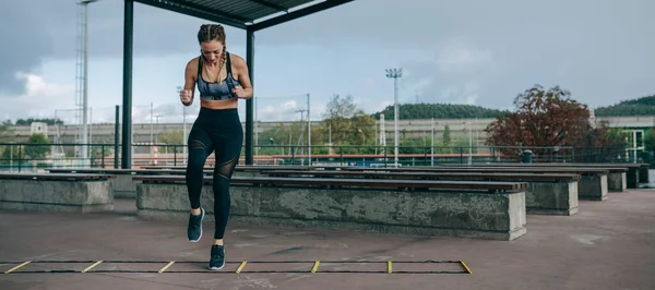 Deportiva saltando en una escalera de agilidad — Foto de Stock