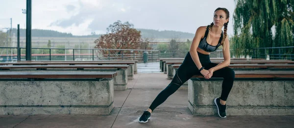 Deportiva posando sentada en un banco — Foto de Stock