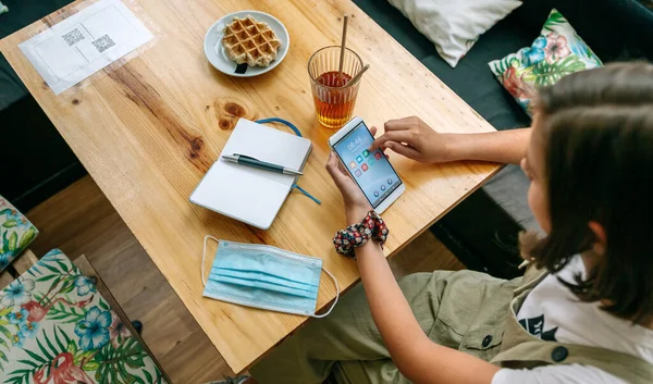 Woman in a coffee shop with face mask on the table — Stock Photo, Image