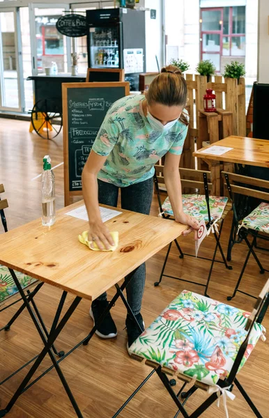 Garçonete desinfetando mesas em um café — Fotografia de Stock