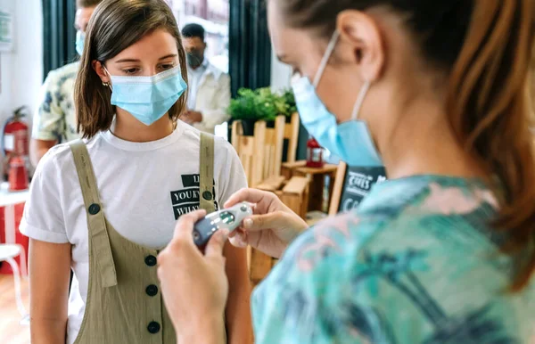 Geschäftsinhaberin schaut auf das Thermometer, das ihre Mitarbeiter überprüft — Stockfoto