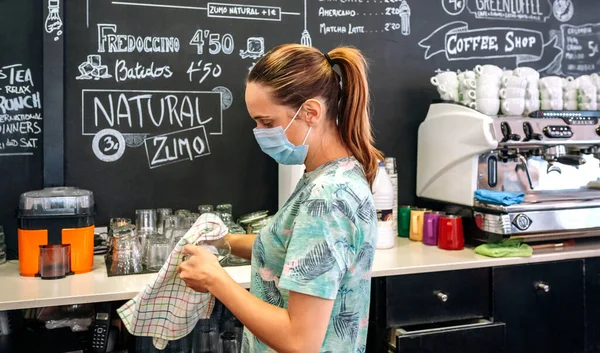 Waitress with mask cleaning glasses — Stock Photo, Image