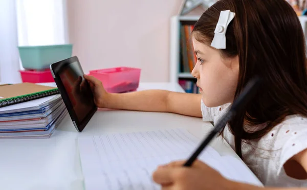Девочка делает домашнее задание с планшетом — стоковое фото