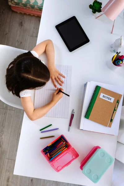 Dziewczyna odrabia lekcje siedząc przy biurku — Zdjęcie stockowe