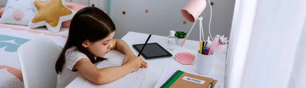 Дівчина навчається вдома з маскою на столі — стокове фото