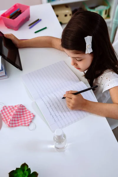 Chica estudiando en casa con máscara y gel desinfectante —  Fotos de Stock