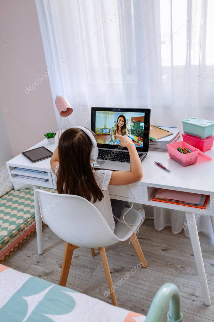 Girl at home receiving online class from her teacher