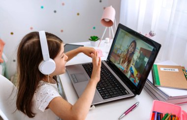 Kız öğretmeninin online dersini izliyor.