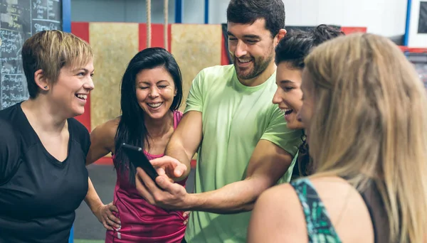 Athletes looking at the mobile of a gym mate — Stock Photo, Image