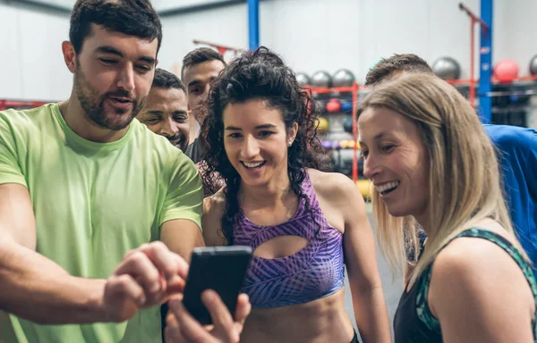 Sportler schauen auf das Handy eines Sportkameraden — Stockfoto