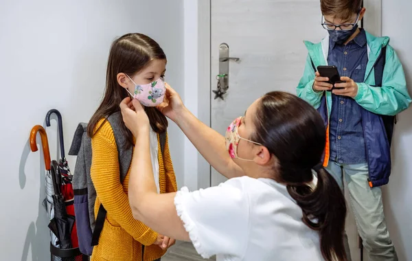 Madre poniéndole la máscara a su hija — Foto de Stock