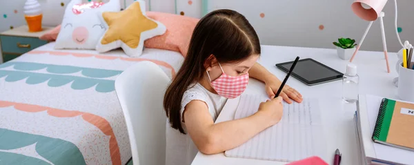 Girl with mask doing homework in her bedroom — Stock Photo, Image