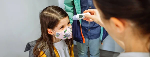 Madre revisando la temperatura de sus hijas antes de ir a la escuela — Foto de Stock