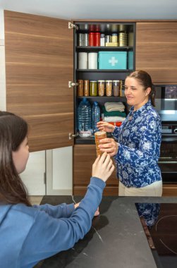 Anne ve kız acil durum kilerine su, konserve yiyecek ve ilk yardım çantası da dahil olmak üzere kurabiye paketleri ekliyor. Doğal afet ya da elektrik kesintisi için 72 saat hayatta kalma kiti hazırlayan aile.