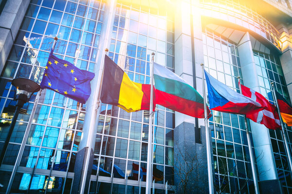 Waving flags in front of European Parliament building. Brussels, Belgium
