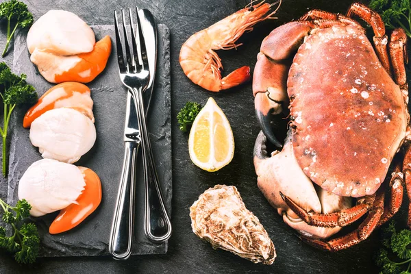 晚餐甲壳类动物的精选 在黑暗背景上有餐具的螃蟹 扇贝和牡蛎 — 图库照片