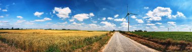 Kırsal yol ve rüzgar türbinleri ile panoramik yaz manzarası. Ekoloji arka planı
