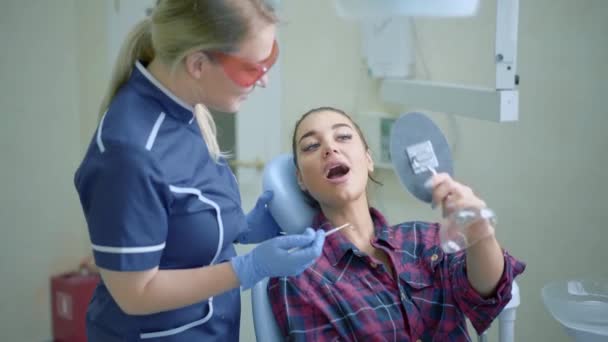Vrouwelijk tandarts tonen voor de patiënt resultaat van de behandeling — Stockvideo