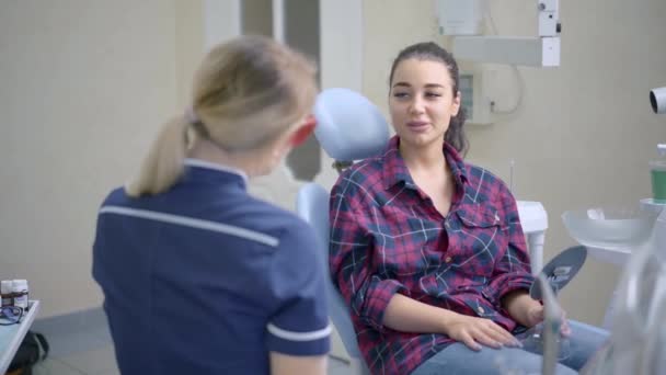 Женщина-дантист разговаривает с пациентом в стоматологической клинике — стоковое видео