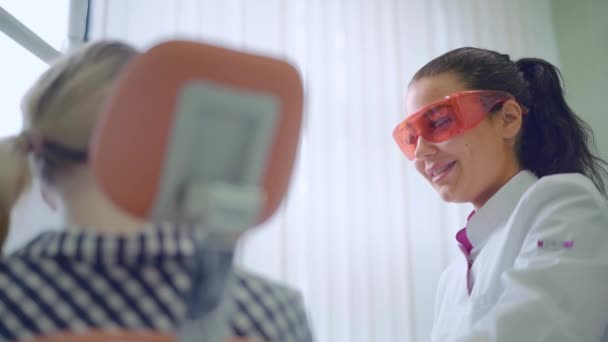 Atractivo dentista hablando con una paciente joven en la clínica dental — Vídeo de stock