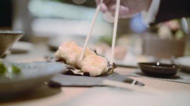 Suşi roll bölümünü alarak yemek çubukları
