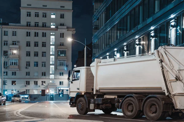 Biały samochód ciężarowy w nocy miasto obok nowoczesnych budynków. — Zdjęcie stockowe