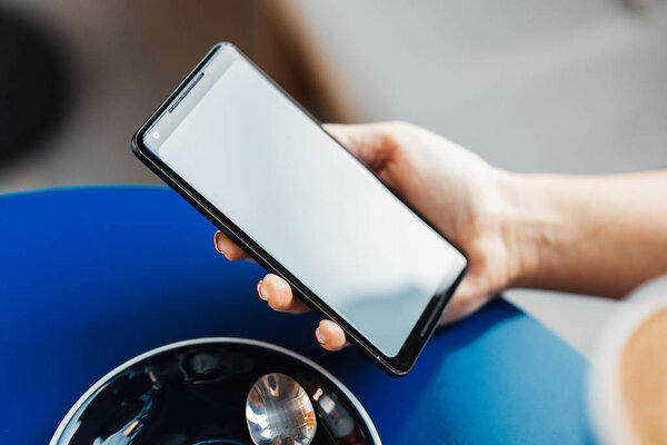 Close up of woman hands holding mobile phone with blank screen.