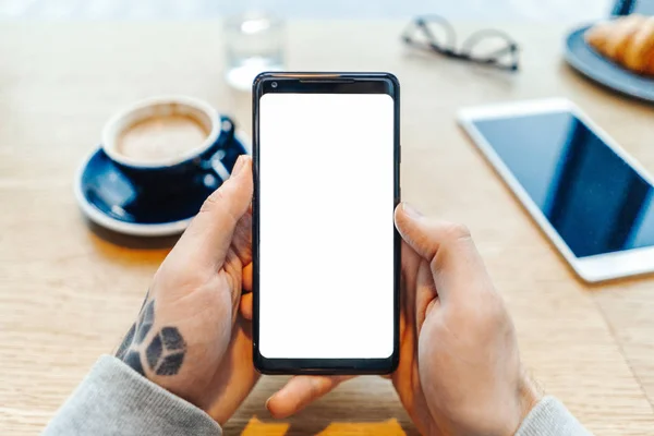 Close up de homem tatuado mãos segurando telefone celular com tela em branco . — Fotografia de Stock