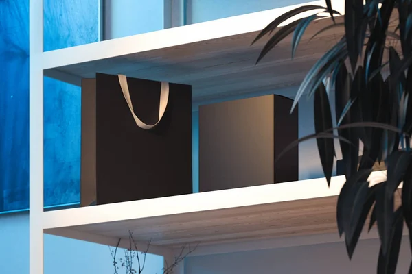 Black shopping bag with white handles on wooden shelf. 3d rendering. — Stock Photo, Image