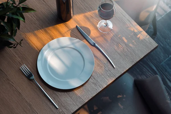 Weißer Teller auf Holztisch neben stilvollem Geschirr. 3D-Darstellung. — Stockfoto