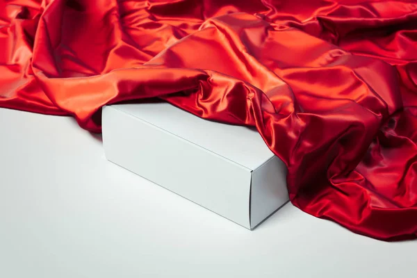 Gros plan de la boîte blanche vide sous le tissu rouge sur fond blanc. Rendu 3d . — Photo