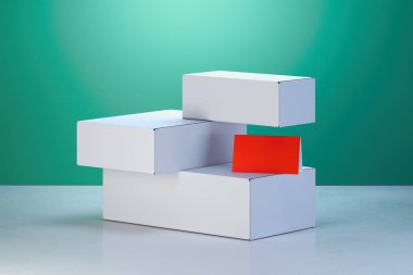 Yeşil arka planda beyaz karton kutular ve kırmızı boş kartvizit. 3d render.