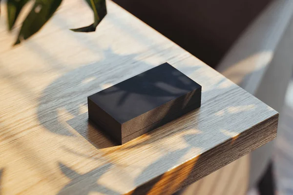 Κοντινό χρώμα μαύρου κενού φωτισμένο από τις επαγγελματικές κάρτες ημέρας που έχουν ρυθμιστεί σε ξύλινο τραπέζι, απόδοση 3D. — Φωτογραφία Αρχείου