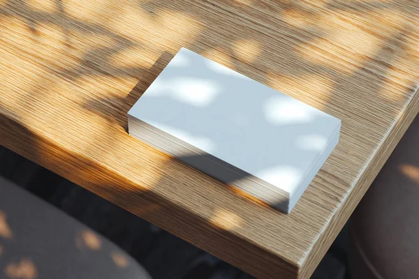 Κλείσιμο λευκού κενού που φωτίζεται από τις επαγγελματικές κάρτες ημέρας που έχουν οριστεί σε ξύλινο τραπέζι, απόδοση 3D. — Φωτογραφία Αρχείου
