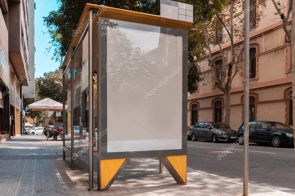 Blank canvas white outdoor banner at bus stop next to facade of ancient building at european town. Empty outdoor billboard.
