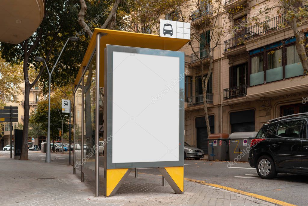 Blank canvas white outdoor banner at bus stop next to facade of ancient building at european town. Empty outdoor billboard.