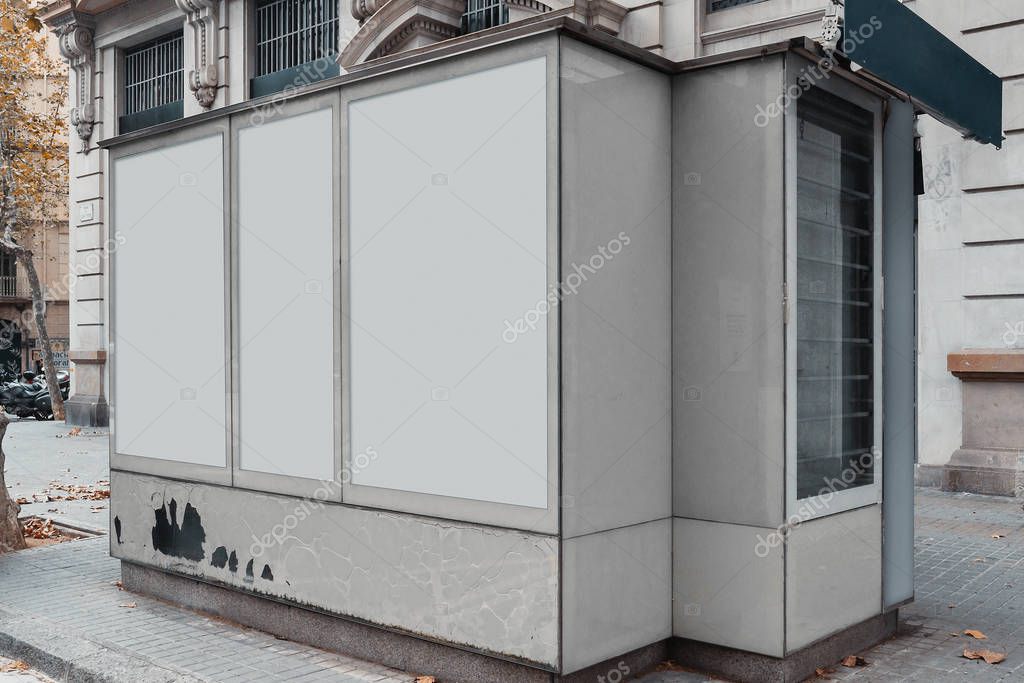 Blank canvas white outdoor banner at Newsstand with newspapers and magazines.Press kiosk next to facade of ancient building at european town