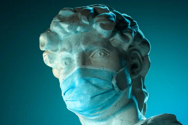 Vue latérale du buste de la tête Sculpture classique portant un masque protecteur contre le virus sur fond bleu illuminé de lumière au néon. Rendu 3d — Photo