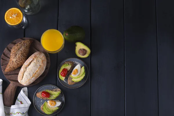 Tasty and juice , sandwich with avocado, tomato and poached egg on wooden chopping board, close up, selective focus. Healthy delicious breakfast or lunch. On a dark background, flat lay . copy space