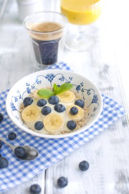 Lezzetli breakfast kompozisyon. Muz, linseeds, taze meyve, kahve, fover rustik ahşap zemin, kopya alanı ile organik müsli kase. Üstten görünüm