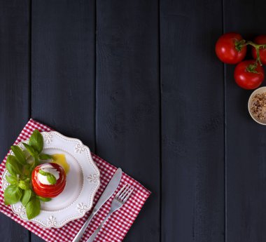 Geleneksel İtalyan Caprese salatası - dilimlenmiş domates, mozzarella peyniri ve fesleğen, koyu arka plan, üstten görünüm, boşaltmak. Caprese salatası, İtalyan Akdeniz yemekleri.