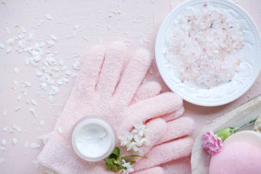 Spa El Bakımı, deniz tuzu ve eldiven. Çiçekler beyaz. Pembe bir arka plan.