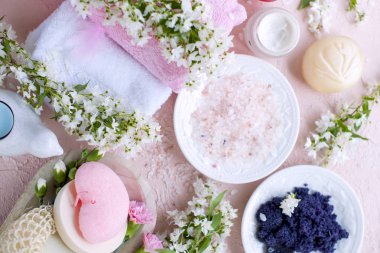 Spa. Farklı kozmetik bakım ve güzellik için. Pembe bir arka plan ve çiçekler. Metin için yer. Deniz tuzu