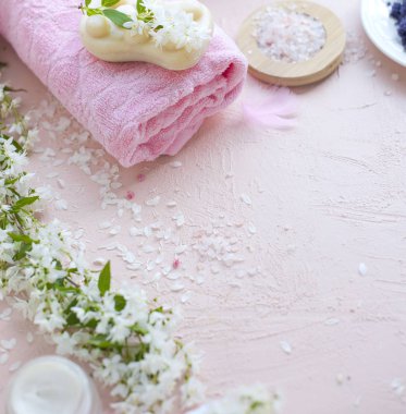 Spa. Havlu, deniz tuzu ve sabun. Pembe bir arka plan ve çiçekler. Metin için yer.
